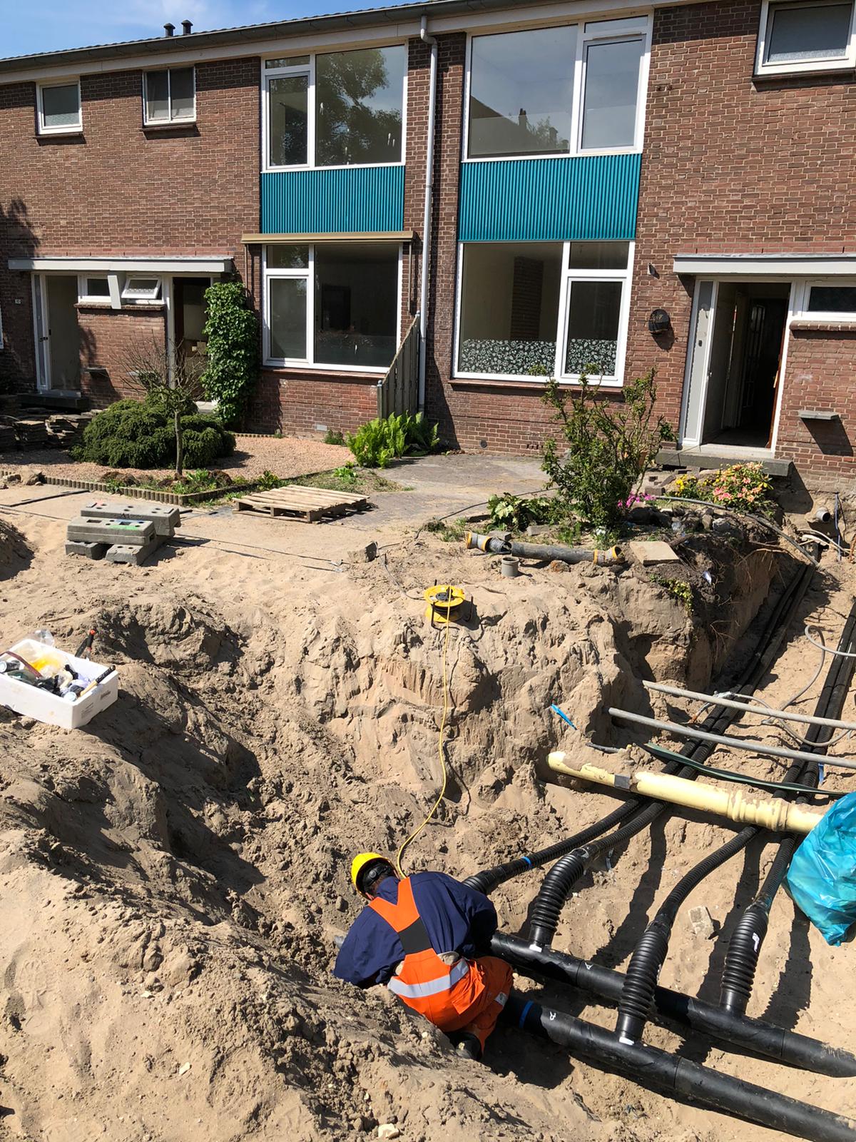 medewerker aannemer legt in een sleuf leidingen aan voor het warmtenet