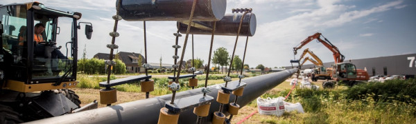 Kraan tilt een leiding van het warmtenet op zijn plek