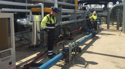 Twee medewerkers staan bij de leidingen van het aardwarmteproject Trias Westland