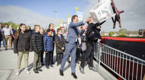 wethouder Arno Janssen en Gertjan de Waard, directeur HVC, gooien een tuinstoel en een kruk in de bak voor harde kunststoffen op het ABS kinderen staan erbij te kijken