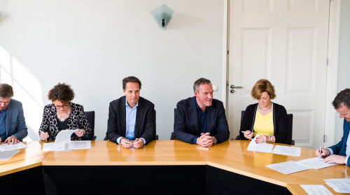 Vertegenwoordigers van de woningcorporaties en HVC zitten aan tafel en ondertekenen een intentieovereenkomst