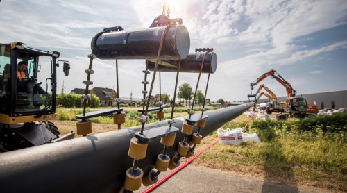 Kraan tilt een leiding van het warmtenet op zijn plek