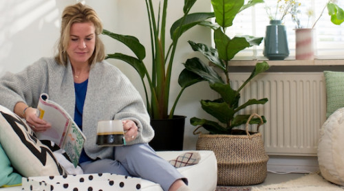vrouw op de bank in de woonkamer, lees een tijdschrift. radiator op de achtergrond.