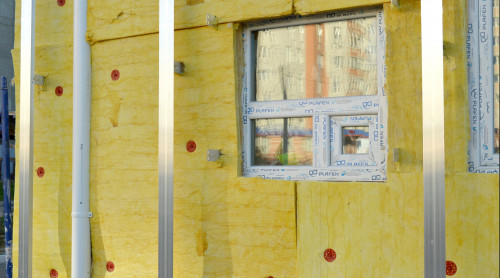 Onafgewerkte muur waar isolatie materiaal duidelijk zichtbaar is.