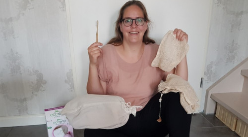 Inge zit op de vloer tegen de muur.In haar rechterhand en op haar schoot liggen katoenen zakken. Op de grond links ligt een ecoegg en voor haar liggen watjes en potjes