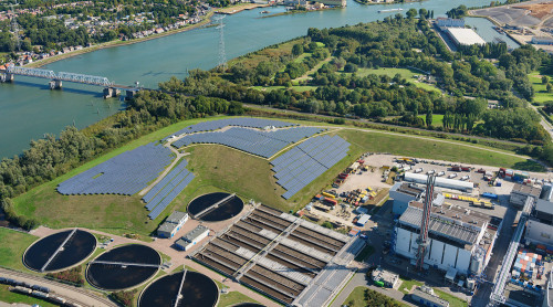 Zonnepanelen op een oude vuilnisbelt gezien vanuit de lucht met op de achtergrond water, waterzuiveringsbasis en de afvalenergiecentrale van HVC