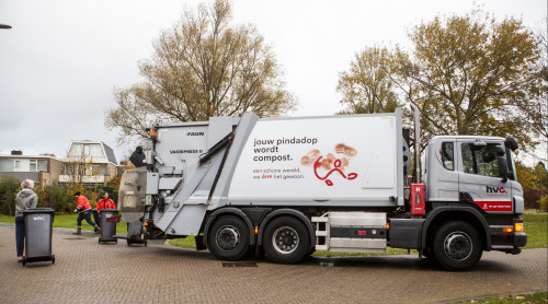 Wagen staat klaar om bakken te legen. Twee chauffeurs brengen de bakken naar de wagen. Een meneer komt nog snel zijn bak brengen om te legen.
