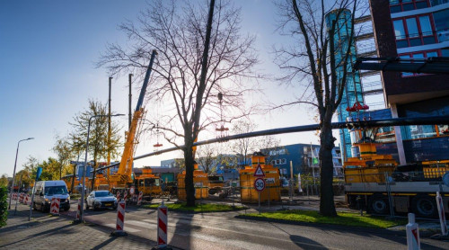 Foto van de werkzaamheden op de Deltalaan waarbij een lange leiding van 540 opgetild wordt door vier grote hijskranen