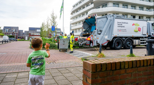HVC chauffeurs zwaaien naar jongen tijdens inzamelen papier