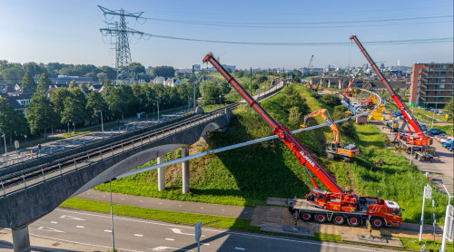 Hijskranen houden leiding vast die onder de verhoogde treinrails doorgaat bij project Boring onder de Merwede