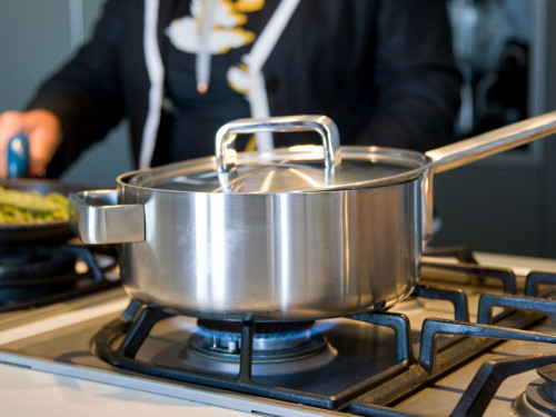 Vrouw bereid eten in een pan op gaspit