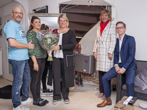 In de huiskamer van de bewoners - van links naar rechts de heer en mevrouw Zayas, Nicole van Wijk van Woonwaard overhandigt bos bloemen aan bewoners, wethouder Monique Stam en Marco van Soerland van HVC. Fotografie door Rick Akkerman