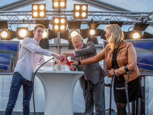 Drie mensen verrichten een symbolische openingshandeling op de achtergrond schijnen spots