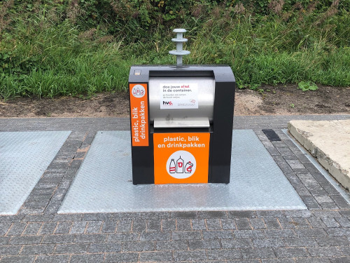 plastic blik en drinkpakken verzamelcontainer op straat met natuur op de achtergrond.