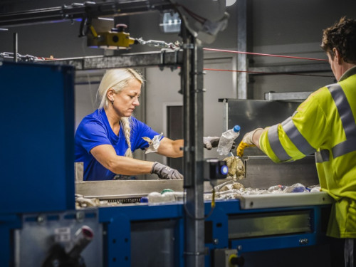 Vrouw sorteert plastic met de hand in kunststofsorteerinstallatie