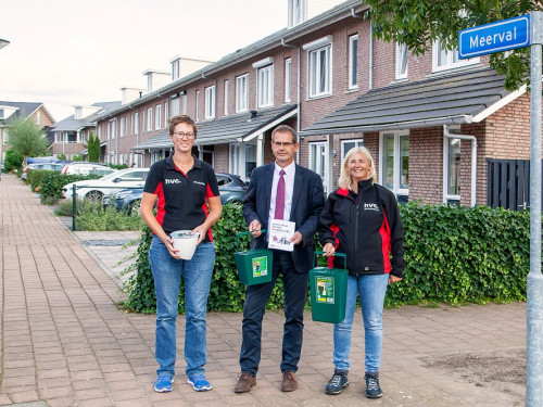 Links en rechts in rood en zwart staan de afvalcoaches van HVC. In het midden de wethouder van Hendrik-Ido-Ambacht. In hun hand hebben zij een emmertje waarin je gft en etensresten kunt in doen.