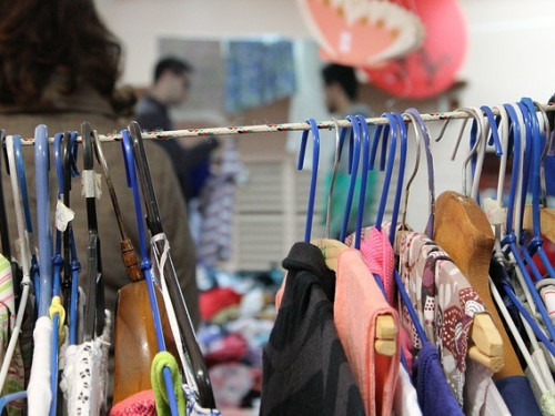 Tweedehands kleding op hangers in een kringloopwinkel