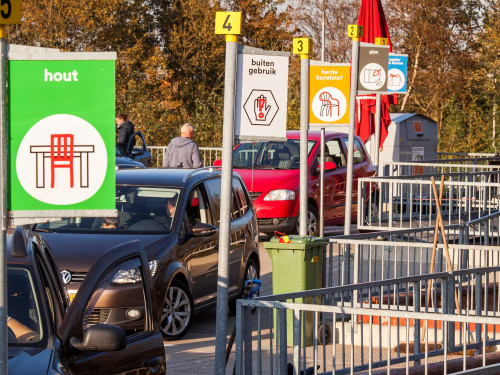 Auto's staan bij containers op het afvalbrengstation om grof afval in te leveren