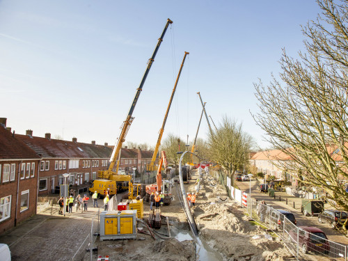 warmteleiding wordt ingetrokken door grote hijskranen in een straat