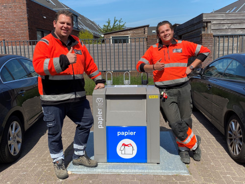 Twee chauffeurs staan naast een ondergrondse papiercontainer in de wijk