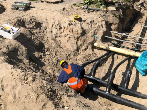 medewerker aannemer legt in een sleuf leidingen aan voor het warmtenet