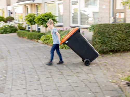 Jongen zet plasticbak aan de weg