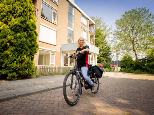 afval coach Astrid op de fiets in de wijk