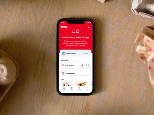 Telefoon met de HVC-app daarop geopend. Daarnaast liggen gepropt papier en een eierdoos