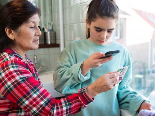 kleindochter en oma gebruiken de afvalwijzer in de HVC-app om te kijken waar de lege tandpastatube in hoort