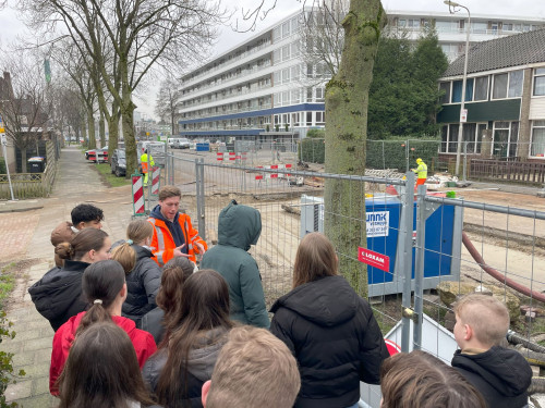 Leerlingen van Het Loket krijgen uitleg van de aannemer over de werkzaamheden voor de aanleg van het warmtenet in Zwijndrecht 