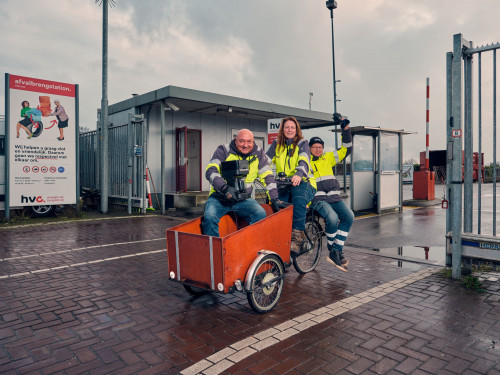 drie medewerkers van het afvalbrengstation rijden op bakfiets naar nieuwe locatie