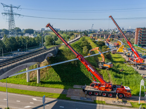 Hijskranen houden leiding vast die onder de verhoogde treinrails doorgaat bij project Boring onder de Merwede