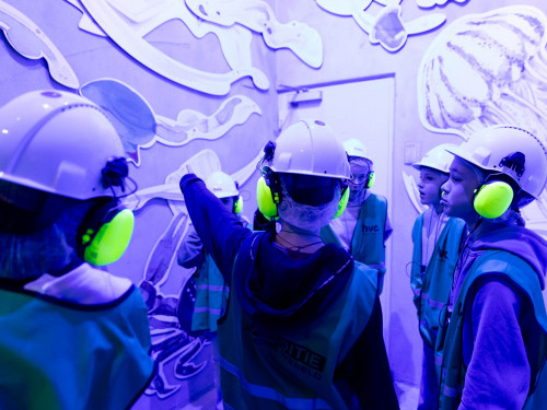 kinderen staan in een blauw verlichte gang en kijken naar illustraties