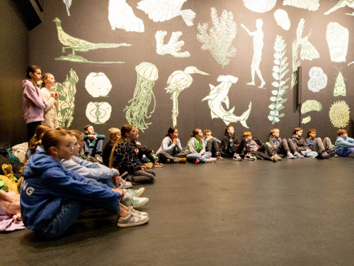 groep kinderen in filmzaal met illustraties op wand