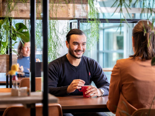 2 collega's in gesprek, met 1 in achtergrond