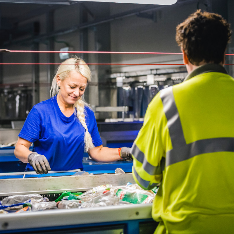 Vrouw aan het werk in de kunststof sorteer installatie